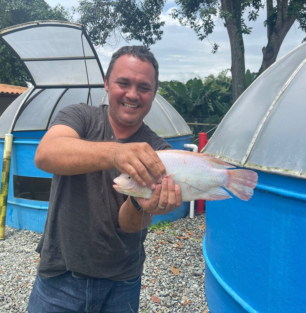 Productor Bofish sosteniendo una tilapia cosechada de su sistema acuapónico